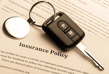 closeup of car keys sitting on insurance documents